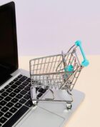 Mini shopping cart on a laptop symbolizes online shopping and e-commerce themes.